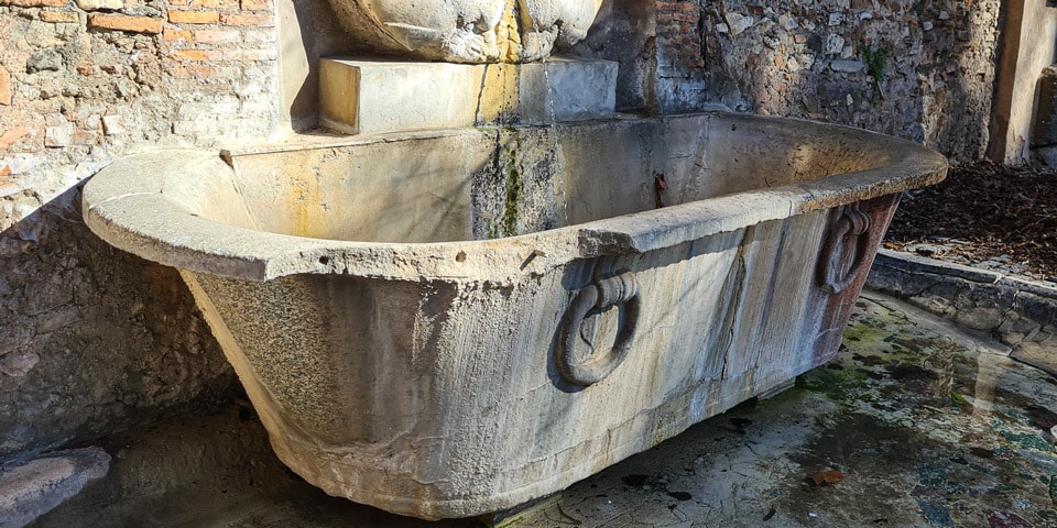 The basin below the mask Fountain is from an ancient Roman thermal bath