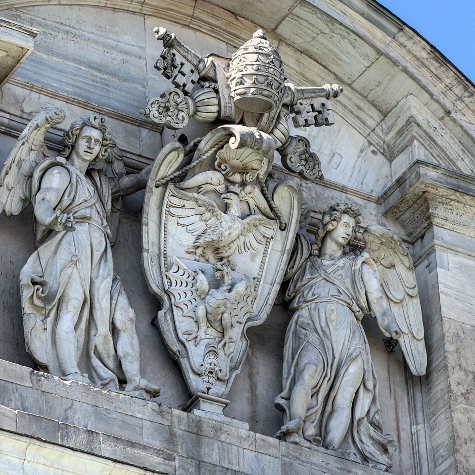 Borghese family crest with papal tiara, crossed keys, eagle and dragon flanked by marble angels on the Acqua Paola fountain, Rome