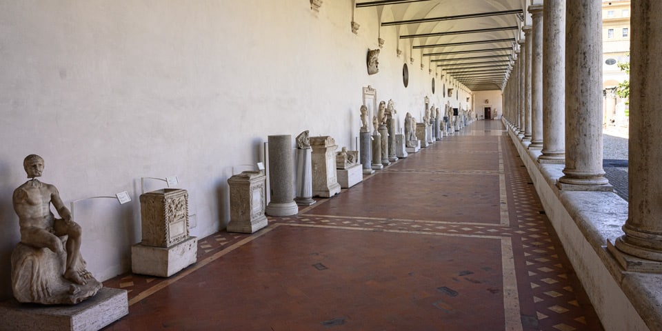 Long colonnaded gallery of the Great Cloister lined with ancient Roman statues and altars, Baths of Diocletian, Rome