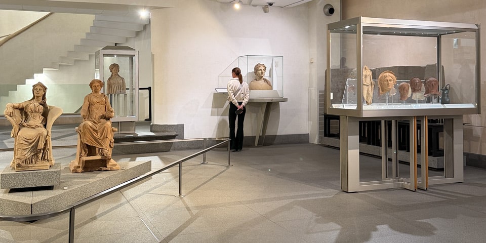 Interior gallery of the National Roman Museum with ancient statues and busts in display cases, Baths of Diocletian, Rome
