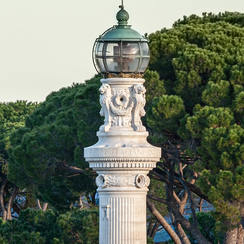 Close view of the glass lantern and lion-headed stone decoration of the Faro del Gianicolo in Rome