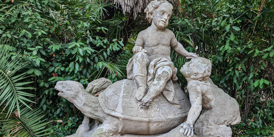 Putto seated on a giant turtle while a young faun climbs beside him at Villa Sciarra in Rome