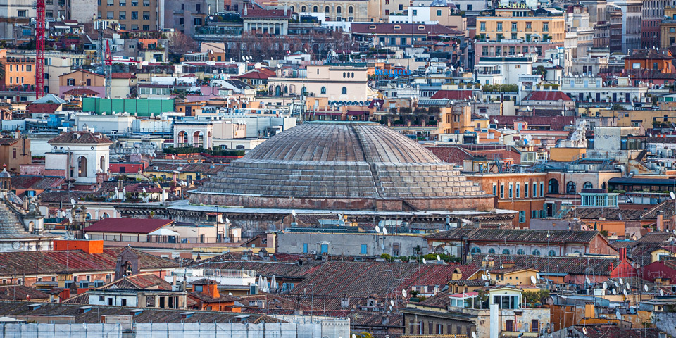 Exterior rings of the Pantheon dome rising among terracotta rooftops, photographed with a telephoto lens from Piazzale Garibaldi, Rome