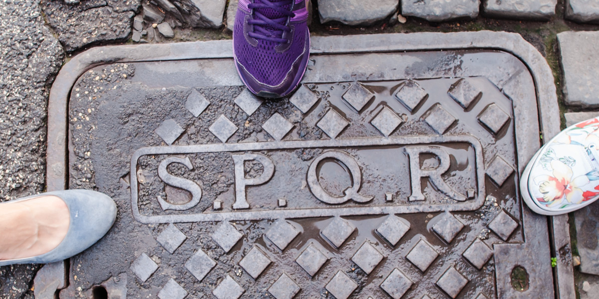 SPQR initials on a metal manhole cover in a cobbled street in Rome